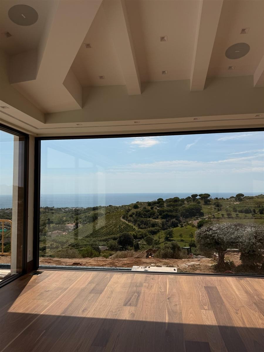 Salón con ventanal panorámico y vistas al mar y viñedos